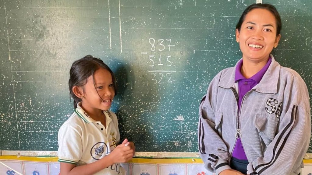 Kanika solving a maths equation on the blackboard with her teacher