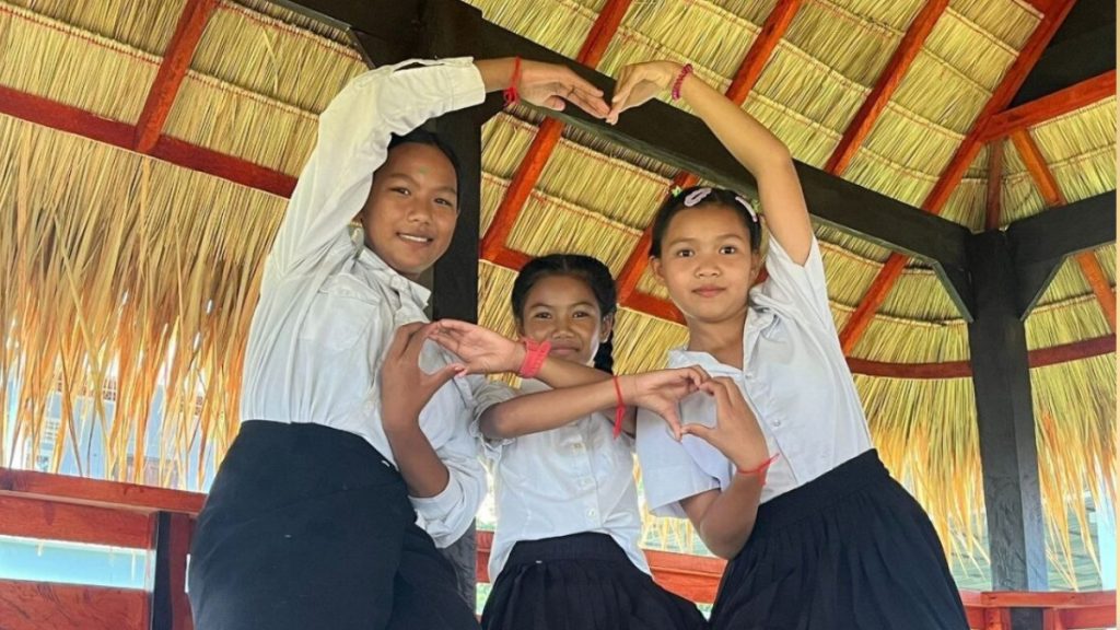 Three young people create a love heart with their arms