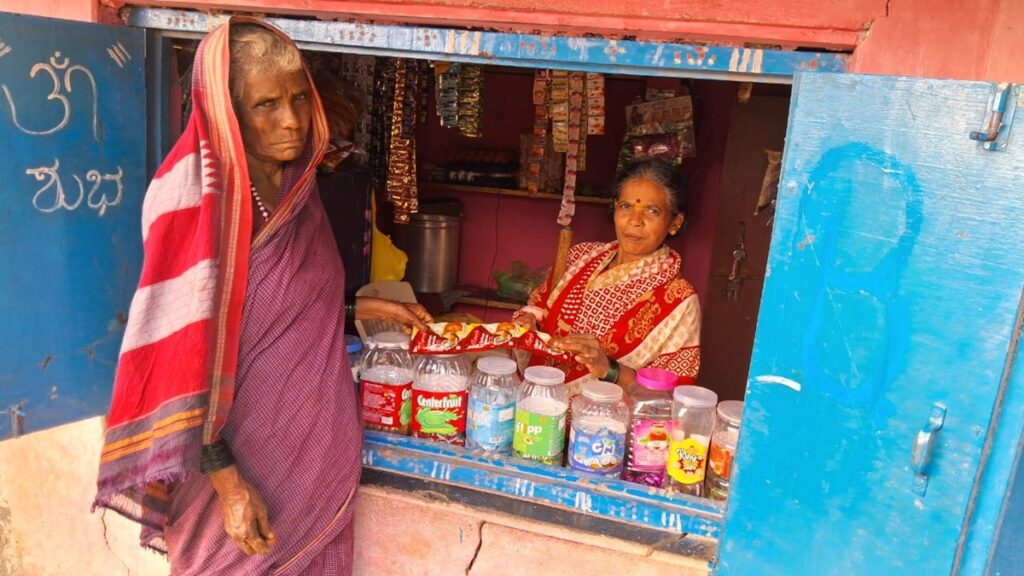 Nagavva sitting in her colourful shop selling to a customer