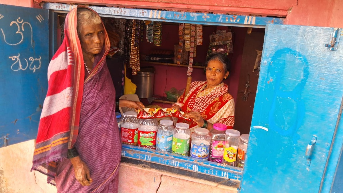 Nagavva sitting in her colourful shop selling to a customer