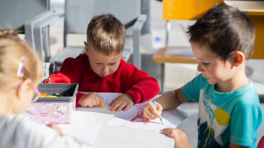 Ukrainian refugee children working at a shared desk in a classroom