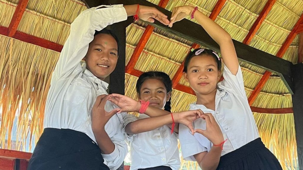 Three pupils form a huge love heart with their arms