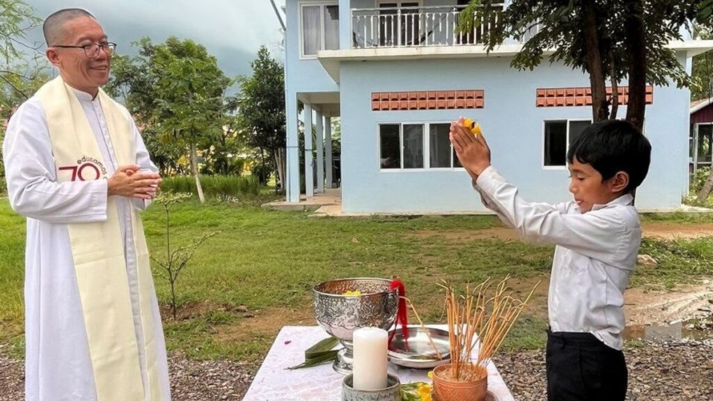 Father Lopez outside the school in prayer with one of the pupils