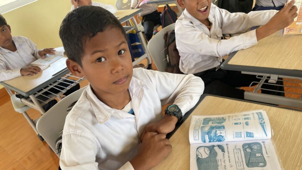 Manut sitting at his schooldesk with a text book open