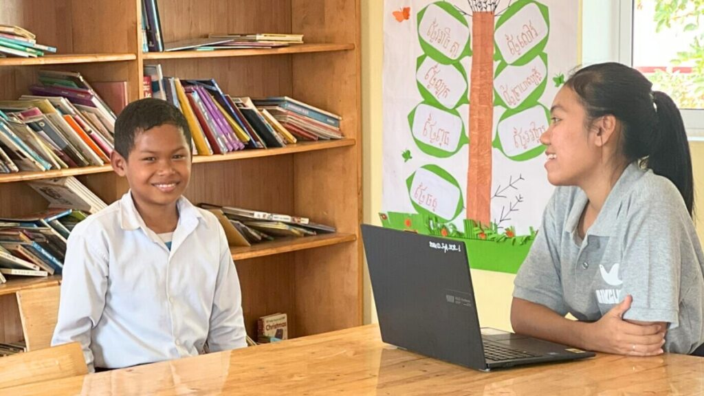 Manut sitting at a desk with one of hte staff members