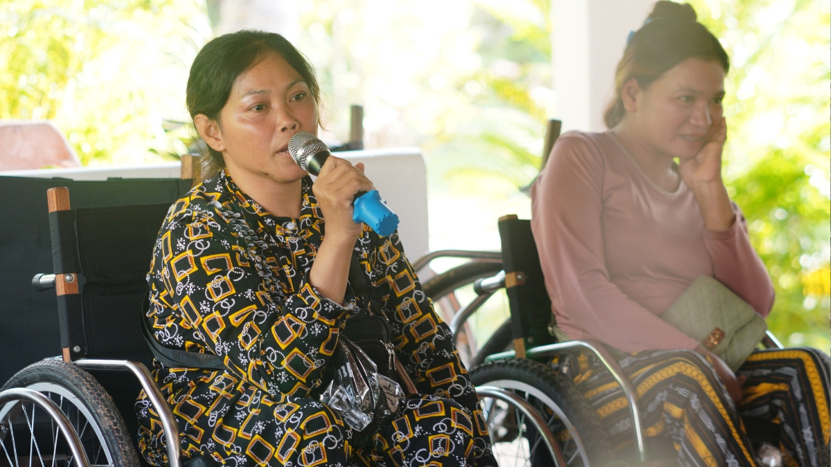 A woman in a wheelchair speaks into a microphone at a community meeting