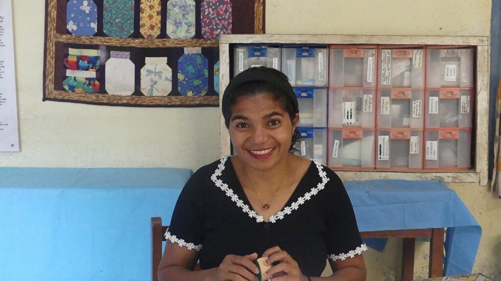 Nivia with her appointment book sitting at a desk in the clinic