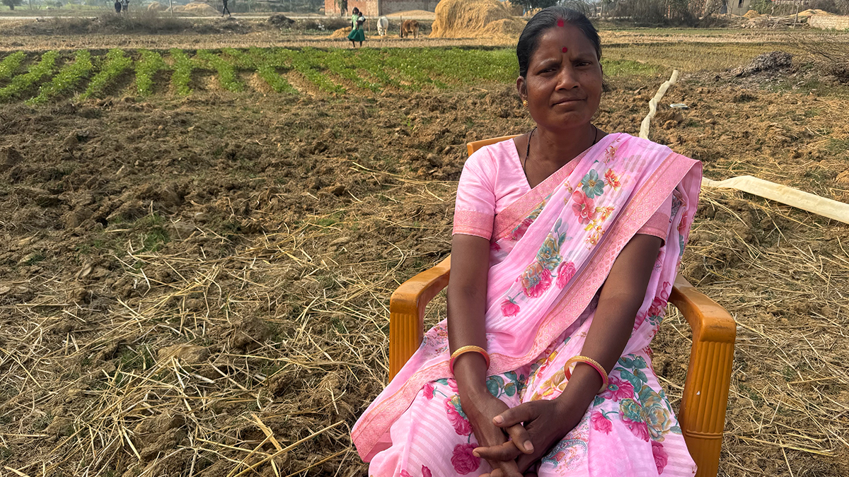 Pratim sitting in a chair in front of a crop field