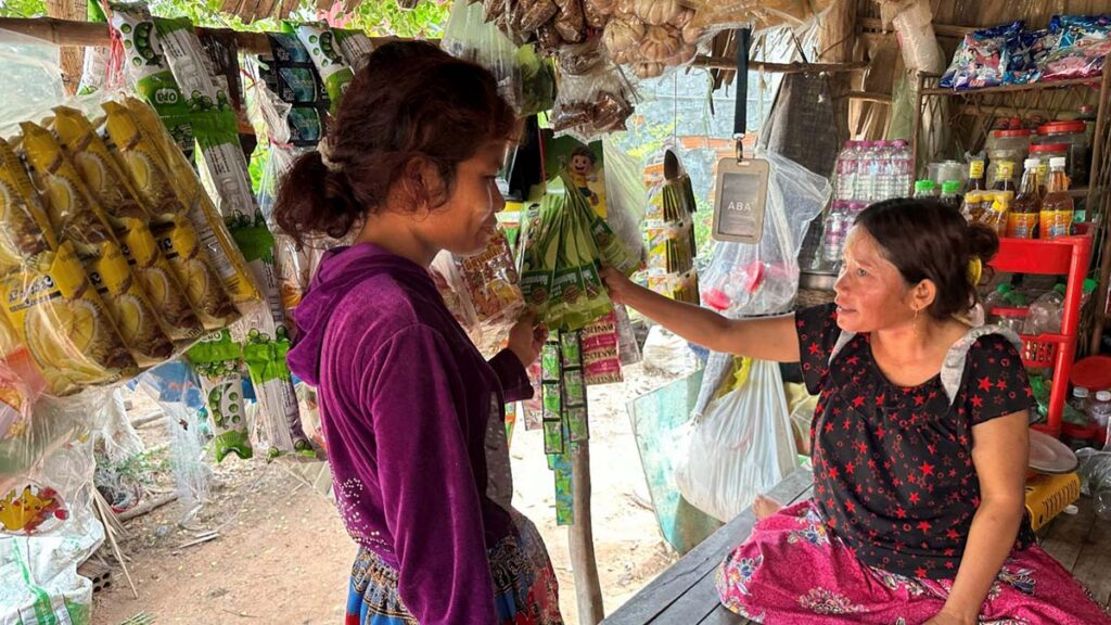 Nga sitting on a platform selling some goods to a customer
