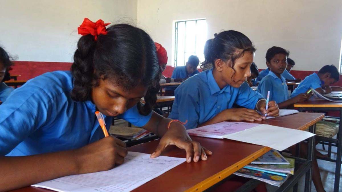 Soni at her school desk writing in her notebook during class
