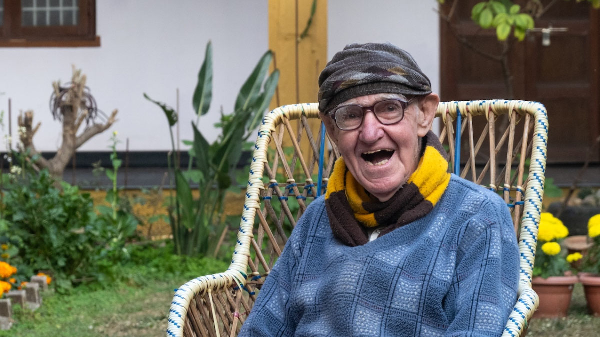 A smiling Father Bob in his garden with his beloved Hawthorn scarf