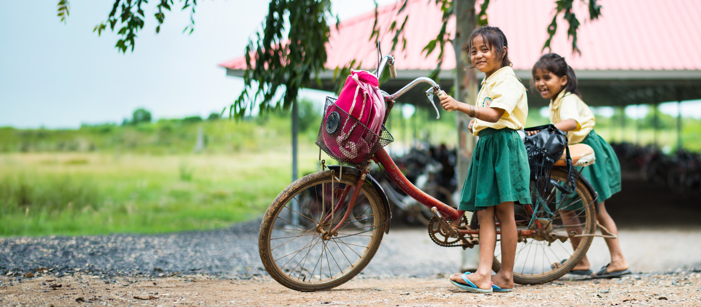 Two Cambodian schoolchildren with a bike on their way to school